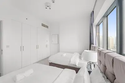 a white room with two beds and a window at FIRST CLASS 3BR Stylish Sanctuary in Dubai