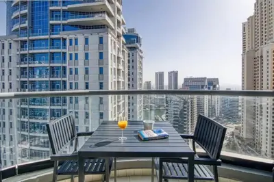 a table with a glass of orange juice on a balcony at FIRST CLASS 3BR Stylish Sanctuary in Dubai
