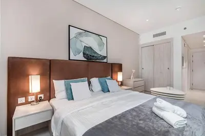 a bedroom with a large bed with blue and white pillows at Cozy studio in Seven Palm in Dubai