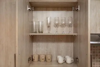 a row of glasses and mugs sitting on a shelf at Lovely 1BR in Seven Palm in Dubai