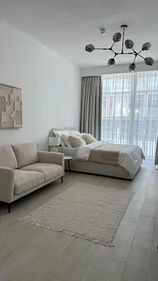 a bedroom with a large bed and a couch at Cozy studio apartment in Jumeirah Village Circle in Dubai