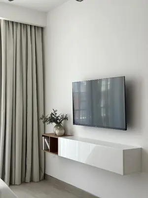 a living room with a tv on a white wall at Cozy studio apartment in Jumeirah Village Circle in Dubai