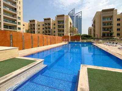 a large swimming pool in a city with tall buildings at Frank Porter - Al Arta 4 in Dubai