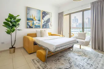 a bedroom with a bed and a couch and a chair at Frank Porter - Al Arta 4 in Dubai