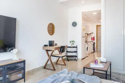 a living room with a desk and a kitchen at Manzil - Stylish living in JVC, City Views and Pool in Dubai