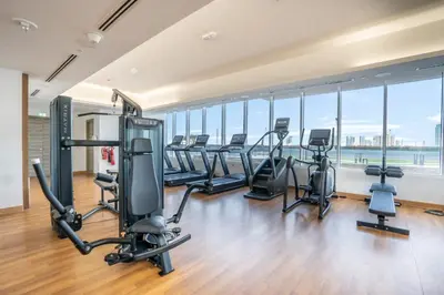 a gym with a row of treadmills and exercise bikes at Manzil - Stylish living in JVC, City Views and Pool in Dubai