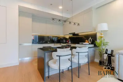 a kitchen with a bar with white stools at The Elegant Escape in Dubai