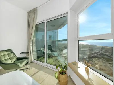 a bedroom with a large window and a chair at Stunning Panoramic Sea & Marina Skyline View in Dubai