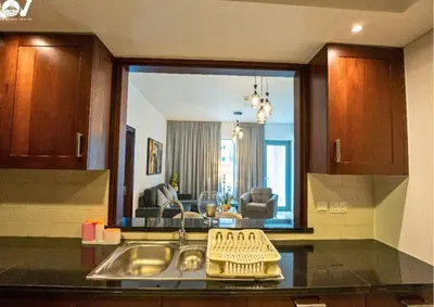 a kitchen with a sink and a living room at Luxurious 2BR I Burj Khalifa View I Downtown Dubai in Dubai