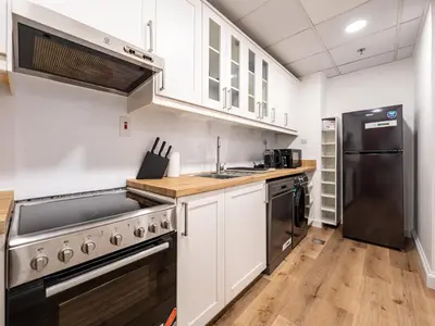 a kitchen with white cabinets and a black refrigerator at Elegant Dubai Eye Beach Retreat in Dubai