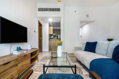 a living room with a couch and a tv at ShoresInn - Stunning 1BR with Marina View in Dubai