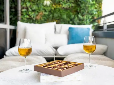 two wine glasses and a box of chocolates on a table at Bespoke 1 Bedroom Apartment I Burj Khalifa & Fountain Views I Free Gym, Pool, Wi-Fi, Parking & PS5 I by Skyline Serenity in Dubai