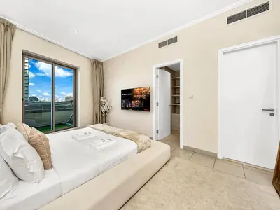 a white bedroom with a large bed and a window at Bespoke 1 Bedroom Apartment I Burj Khalifa & Fountain Views I Free Gym, Pool, Wi-Fi, Parking & PS5 I by Skyline Serenity in Dubai