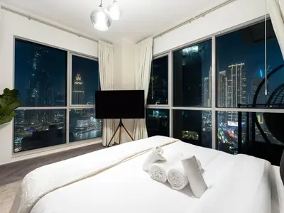 a bedroom with a large window with a bed and a television at Luxe 4 bedroom Apartment I Burj Khalifa & Fountain Views I Free Gym, Pool, Parking, Wi-Fi and PS5 I by Skyline Serenity in Dubai
