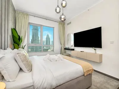a bedroom with a large bed with a flat screen tv at Luxe 4 bedroom Apartment I Burj Khalifa & Fountain Views I Free Gym, Pool, Parking, Wi-Fi and PS5 I by Skyline Serenity in Dubai