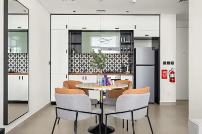 a kitchen with a table and chairs and a refrigerator at Silkhaus in Collective Tower Luxorious 2BDR in Dubai