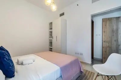 a white bedroom with a bed and a white chair at ShoresInn - Fantastic Marina Waterfront View in Dubai
