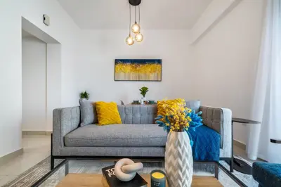 a living room with a couch and a vase with yellow pillows at ShoresInn - Fantastic Marina Waterfront View in Dubai