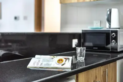 a book on a kitchen counter with a microwave and a glass at ShoresInn - Fantastic Marina Waterfront View in Dubai