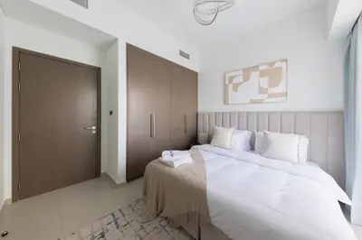 a bedroom with a large bed with a wooden door at Spacious 3BR plus maids Burj Khalifa View in Dubai
