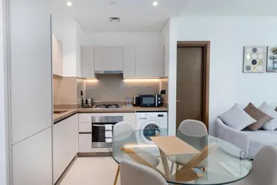 a kitchen and living room with a table and chairs at Ahlan HH - Luxury 2BR in Sobha Creek Vistas in Dubai