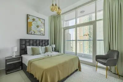 a bedroom with a bed and a chair and a window at ShoresInn - Waterfront in Heart of Dubai Marina in Dubai