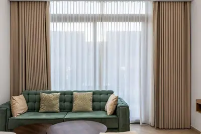 a living room with a green couch in front of a window at Waves - Elegant Oxford 212 Studio in JVC with City Views in Dubai