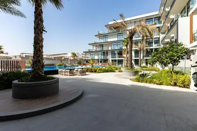 a courtyard with palm trees and a building at Waves - Elegant Oxford 212 Studio in JVC with City Views in Dubai
