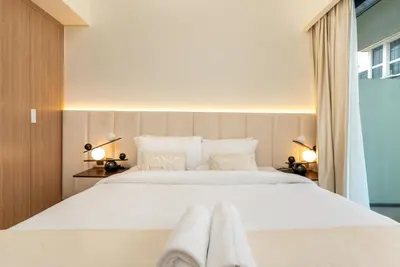 a bedroom with a large white bed with two towels on it at Ahlan HH - Stylish Studio with Pool & Gym, Azizi Riviera 26 in Dubai