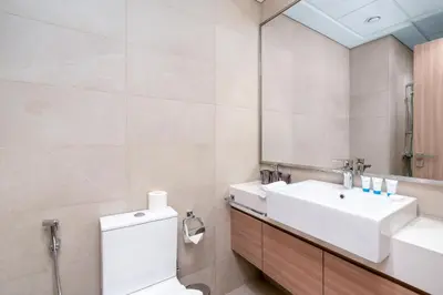 a bathroom with a sink and a toilet and a mirror at Ahlan HH - Stylish Studio with Pool & Gym, Azizi Riviera 26 in Dubai