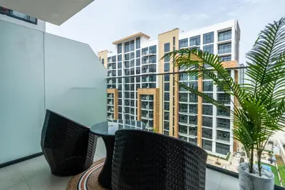 a table and chairs on a balcony with a building at Ahlan HH - Stylish Studio with Pool & Gym, Azizi Riviera 26 in Dubai