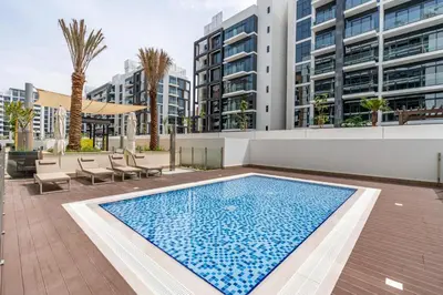 a swimming pool in front of a building at Ahlan HH - Stylish Studio with Pool & Gym, Azizi Riviera 26 in Dubai