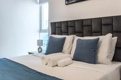 a large bed with blue and white pillows at ShoresInn - Heavenly Escape with Marina View in Dubai