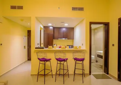 a kitchen with three bar stools at a counter at NiceVisit Merano 1BD Business Bay in Dubai