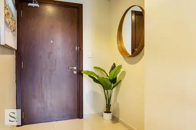 a hallway with a wooden door and a vase with a plant at AWS Holiday Homes - Lux Gateaway near Dubai Mall in Dubai