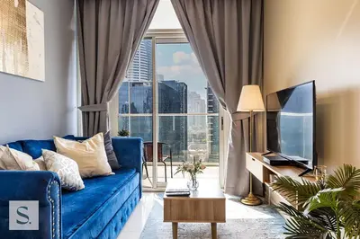 a living room with a blue couch and a large window at AWS Holiday Homes - Lux Gateaway near Dubai Mall in Dubai