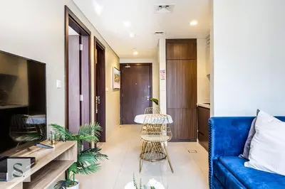 a living room with a blue couch and some plants at AWS Holiday Homes - Lux Gateaway near Dubai Mall in Dubai