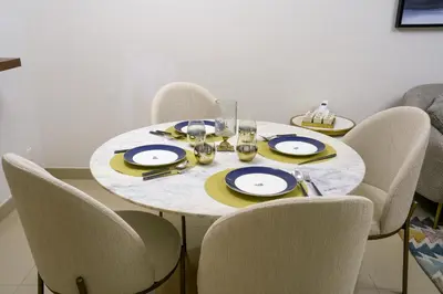 a dining room table with chairs and a white and yellow table at CH Skyline Retreat - Cozy 1BR Apt With Burj Khalifa and Fountain Views in Dubai