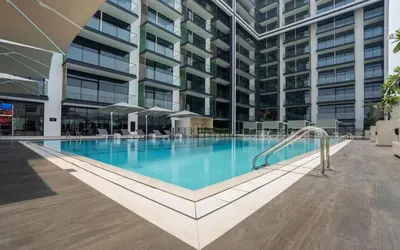 a swimming pool in front of a building at Stylish 1br Apartment Jvc Pool Parking in Dubai