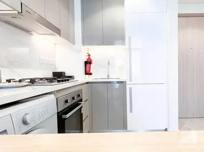 a kitchen with white appliances and a fire extinguisher at Elegant 1BR with Balcony in Azizi Riviera in Dubai