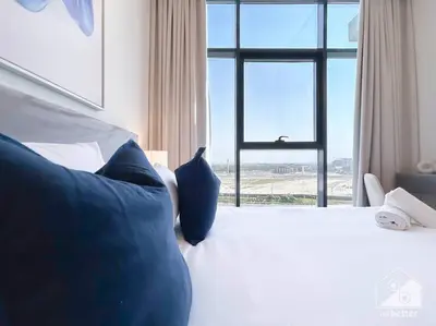 a bedroom with a bed with blue pillows and a window at Elegant 1BR with Balcony in Azizi Riviera in Dubai