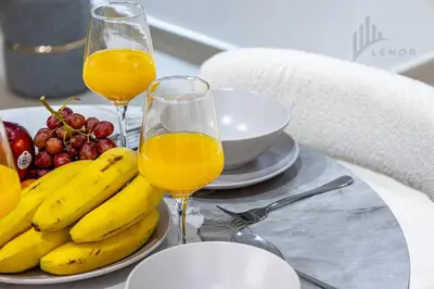 a table with two glasses of orange juice and fruit at Chic 2BR with Partial Burj Khalifa View in Dubai