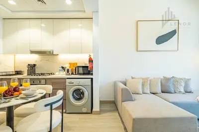 a kitchen and a living room with a couch and a table at Chic 2BR with Partial Burj Khalifa View in Dubai
