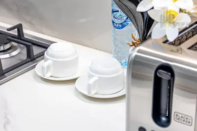 two cups and saucers on a counter next to a stove at Chic 2BR with Partial Burj Khalifa View in Dubai