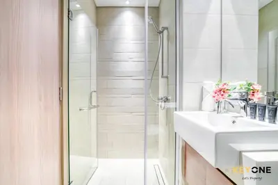 a white bathroom with a shower and a sink at Spacious Azizi Riviera Studio in Dubai