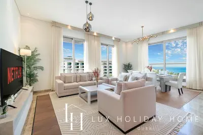 a living room with white furniture and a dining room with the ocean at LUX The Dream Palm Atlantis Sea View Suite in Dubai
