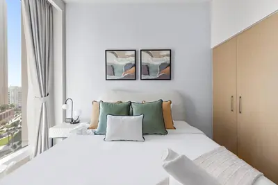a white bedroom with a large bed and a window at FIRST CLASS 2BR Stylish Bliss in Dubai
