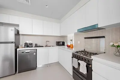 a kitchen with white cabinets and a stove top oven at FIRST CLASS 2BR Stylish Bliss in Dubai