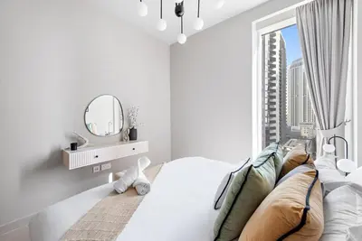 a white bedroom with a large window and a mirror at FIRST CLASS 2BR Stylish Bliss in Dubai
