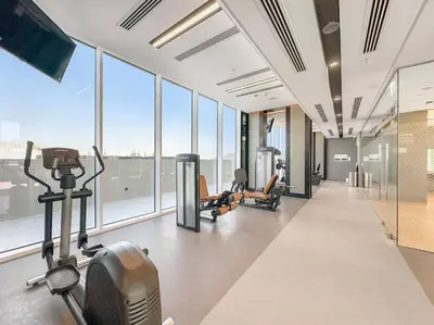 a gym with cardio equipment in a building with windows at FIRST CLASS 2BR Stylish Bliss in Dubai
